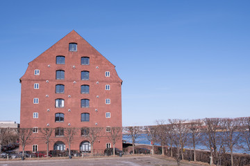 An old warehouse in Copenhagen along the waterfront under a clear blue sky