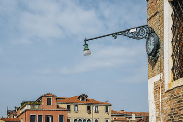 Fototapeta na wymiar Clock and lantern hanging on a corner the house in Venice, Italy.