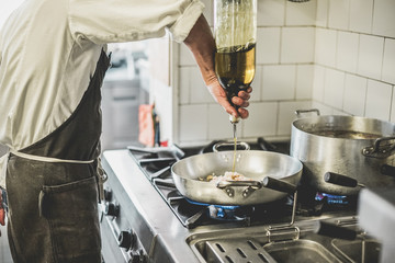 Male chef cooking fresh fish sauce in restaurant kitchen