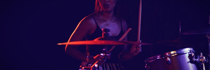 Female drummer playing drum kit in nightclub 