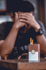 Man in T-shirt are stressed because they want to quit smoking. Focus at Cigarettes Box. Shallow depth of field.