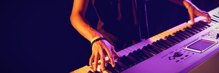 Mid section of male musician playing piano