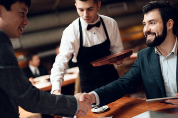 Meeting with chinese businessmen in restaurant. Men are shaking hands.