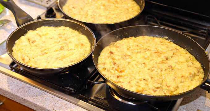 pans with the food named frico a typical italian dish with potatoes and cheese