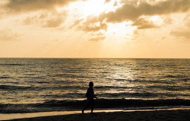 Fototapeta premium People walking on the beach at sunrise happily and the skies are a beautiful light