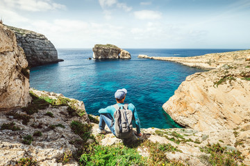 Obraz premium Podróżujący z plecakiem odpoczywają na skalistym wybrzeżu laguny błękitnego morza