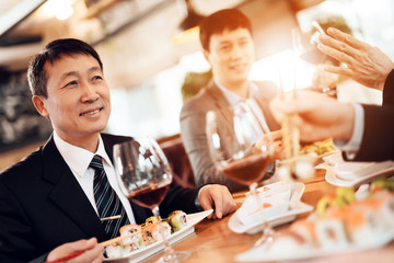 Meeting with chinese businessmen in restaurant. Men are eating sushi.