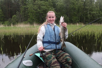 A girl fisherman caught a pike.
