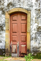 Old and aged historic wooden church door in the city of Ouro Preto, Minas Gerais with a stone frame