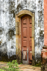 Old and aged historic wooden church door in the city of Ouro Preto, Minas Gerais with a stone frame