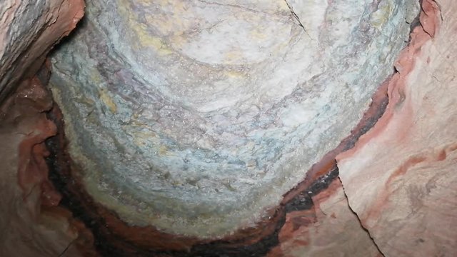 Colored lime-drop drips (dripstone, speleothem) on ceiling of cave, way of formation of stalactites and stalagmites
