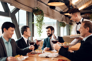 Meeting with chinese businessmen in restaurant. Waiter brings sushi.
