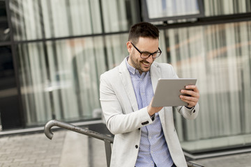 Young businessman with digital tablet by the office building