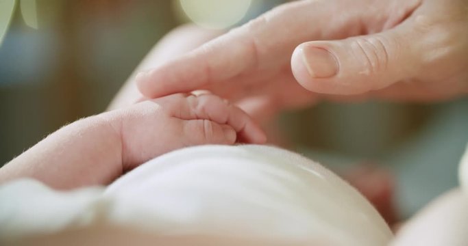 4k.Mother and newborn baby in maternity home. Hand in hand, slow motion, close up. Parenthood. Motherhood. Beautiful bokeh on the background
