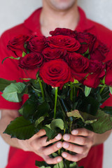 A man close-up gives a bouquet of red roses.