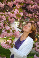 Fototapeta premium A woman with a beautiful smile is happy in the spring. She enjoys the flowering of sakura