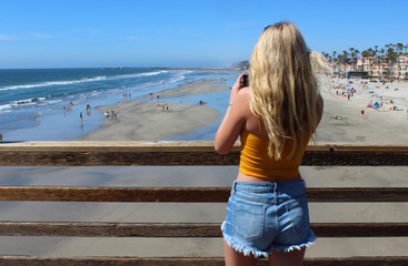 A cute California girl takes a photo of the ocean view from Oceanside Pier