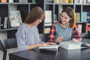 Fototapeta premium Smiling girls with laptop in a bookstore