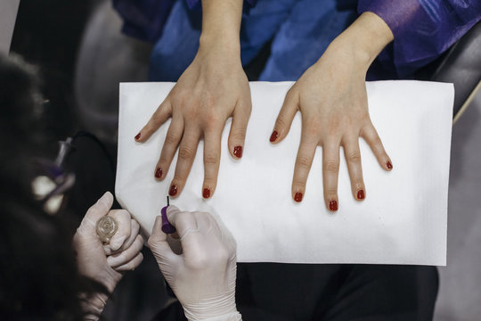 Young woman while applying protective nail polish during a manicure by the beautician