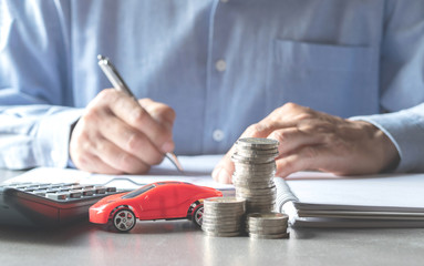 Men are Saint documents about cars  with  some coins calculator and car toy on desk