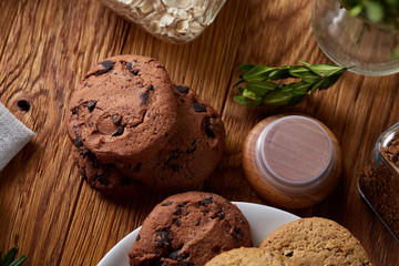 Side view of a plate of chocolate chip cookies on a white plate on homespun tablecloth, selective focus