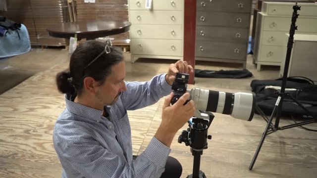 Steadicam to the right as photographer adjusts light levels on top of the camera and takes photos.