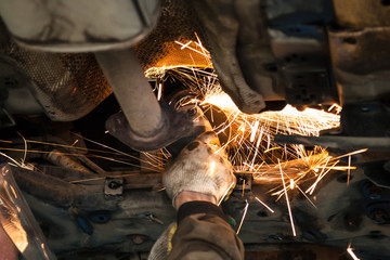serviceman cleans muffler pipe by angle grinder