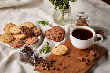 Coffee cup, jar with coffee beans, cookies over rustic background, selective focus, close-up, top view