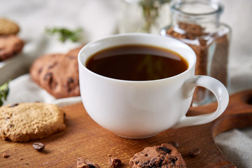 Coffee cup, jar with coffee beans, cookies over rustic background, selective focus, close-up, top view