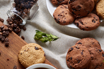 Roasted coffee beans get out of overturned glass jar on homespun tablecloth, selective focus, side view
