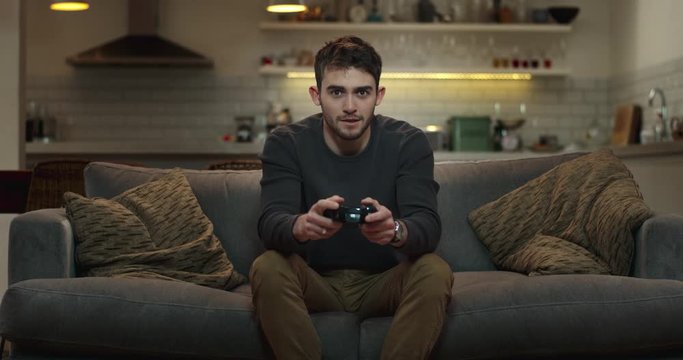 Young man sitting on couch playing video games.