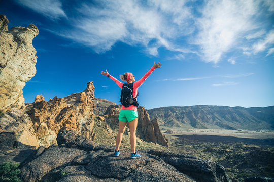 Woman hiker with arms outstretched enjoy mountains