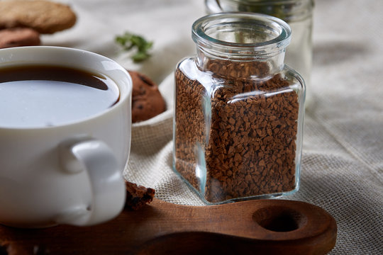Open jar of instant coffee arranged on woden table, top view, close-up, selective focus.