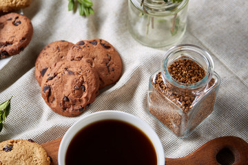 Coffee cup, jar with coffee beans, cookies over rustic background, selective focus, close-up, top view