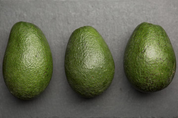Three avocado top view on a dark background .