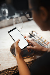 Young brunette girl holding mobile phone while waiting meal