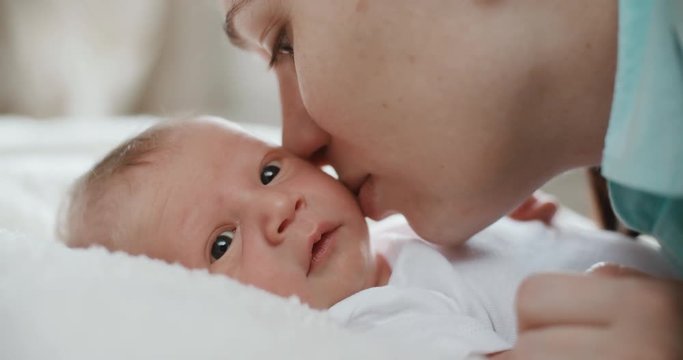 4k.Happy mother and her newborn baby, kissing her child. Resting in bed together. Maternity concept. Parenthood. Motherhood Beautiful Happy Family Slow Motion