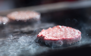Hamburger cutlet frying on pan.Natural meet loaf pieces cooking in the kitchen.Burger sandwich meat being cooked with a lot of white smoke from a fat and oil.