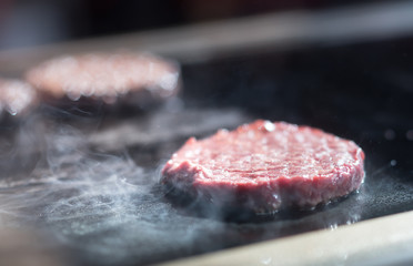 Hamburger cutlet frying on pan.Natural meet loaf pieces cooking in the kitchen.Burger sandwich meat being cooked with a lot of white smoke from a fat and oil.