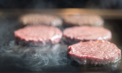 Hamburger cutlet frying on pan.Natural meet loaf pieces cooking in the kitchen.Burger sandwich meat being cooked with a lot of white smoke from a fat and oil.