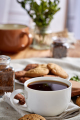 Morning coffee in white cup, chocolate chips cookies on cutting board close-up, selective focus