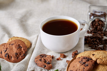 Morning coffee in white cup, chocolate chips cookies on cutting board close-up, selective focus