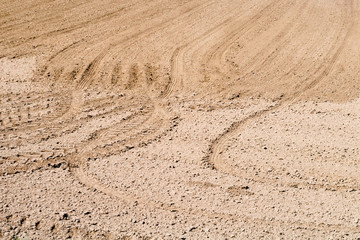 Plowed field. Drawing on the ground furrows and traces of tractor tires