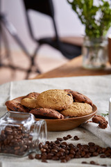 Roasted coffee beans get out of overturned glass jar on homespun tablecloth, selective focus, side view