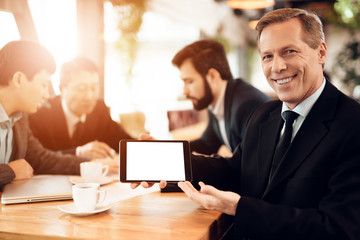 Meeting with chinese businessmen in restaurant. Man showing tablet at camera.