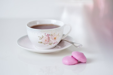 Cup of tea with pink meringues on a white background. Holiday card. Soft focus, copy space. Spring concept.