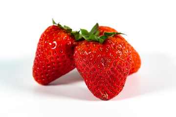 Drei reife Erdbeeren mit Grün isoliert auf weißem Hintergrund