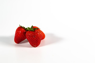 Drei reife Erdbeeren mit Grün isoliert auf weißem Hintergrund