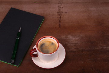 Notebook with pen and coffee cup on wooden background, business concept