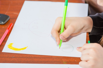 The child is drawing. Draws on a piece of paper. Children have fun. Draws a postcard. The child draws with a pencil.